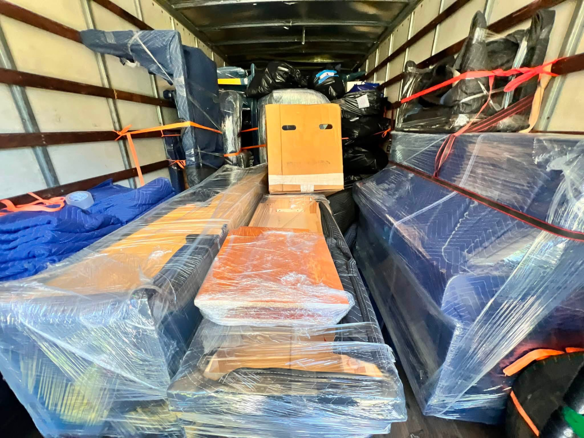 PJ Fast Movers box truck loaded with shrink-wrapped furniture and orange straps